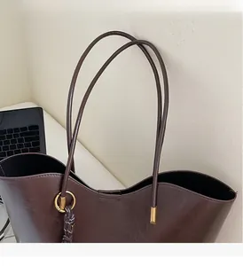 Close-up of brown tote bag showing smooth matte texture and durable metal handle rings