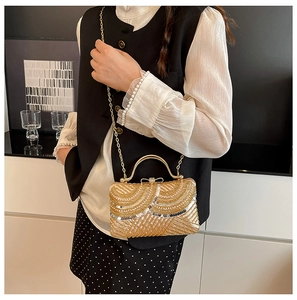 Detail of luxury gold sequin clutch bag with wavy pattern and golden metal handle
