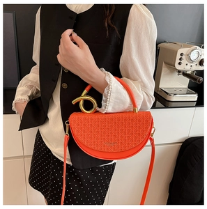 Detail of orange woven saddle bag featuring a pearl handle and gold metal ring accent