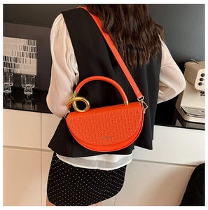 Fashionable orange saddle bag featuring woven texture flap and golden hardware accents