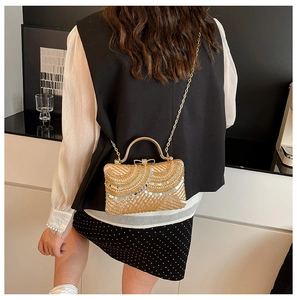 Rear view of model wearing a gold sequined evening bag with chain strap and bow handle