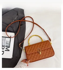 Detail of brown quilted faux leather bag with bamboo handle and gold oval metal clasp