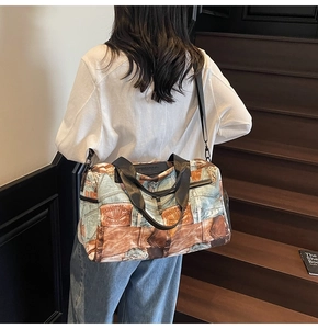 Detail einer Reisetasche im Denim-Print mit Reißverschlusstaschen und verstellbarem Schultergurt