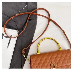 Detailed macro of a brown quilted box bag with a golden bamboo-shaped metal handle