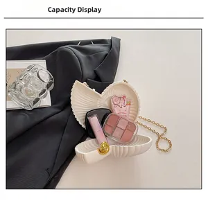 Detail of cream conch clutch bag interior capacity for cosmetics with gold chain strap