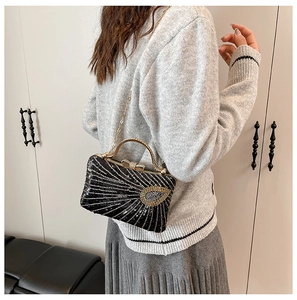 Detail of black sequined evening bag with golden circular handle and chain strap on shoulder