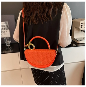 Detail of orange woven half-moon bag with gold ring handle and removable strap