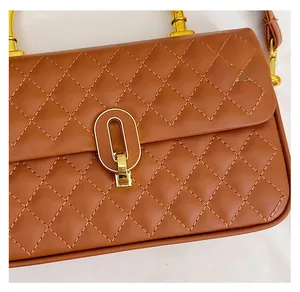 Detail of brown quilted faux leather bag with golden oval twist lock and stitching