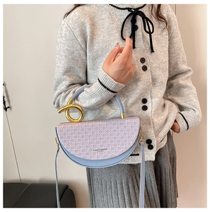 Detail of light blue and purple woven saddle bag with gold ring handle and shoulder strap