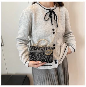 Close-up of elegant black sequin evening bag with crystal peacock pattern and gold handle