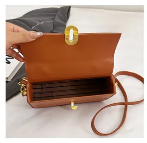 Detail of the brown crossbody bag showing striped lining and golden metal twist lock