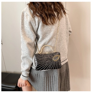 Rear view of a model carrying a black sequin evening bag with gold beaded sunburst pattern