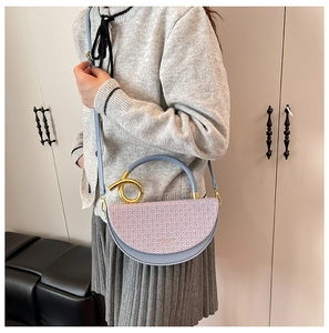 Detail of lavender saddle bag with woven texture, golden ring handle and crossbody strap