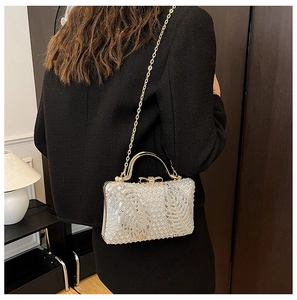 Close-up of sparkling silver sequin evening bag with gold metal handle and chain strap