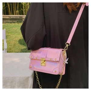 Detail of pink laser crocodile-patterned crossbody bag with a golden turn-lock buckle