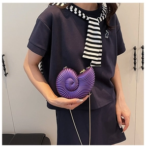 Detail of purple nautilus seashell clutch bag with gold chain strap on model