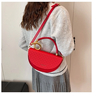 Detail of red semi-circular crossbody bag with woven texture and gold ring handle