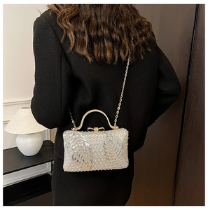 Detail of silver sequin evening bag with gold handle and bow clasp on model