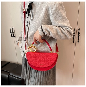 Detail of red semicircular handbag with woven texture and bold gold ring handle ornament