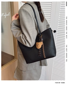 Close-up of black lychee grain tote bag featuring a cute brown plush bear charm