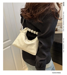 Detail of cream dumpling bag with pearl handle and animal texture shown on model