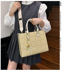 Detailed side view of tote bag featuring monogram pattern and elegant silk scarf accessory