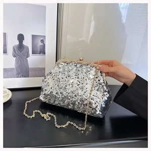 Detail of silver sequin shell bag featuring rhinestone ball clasp and golden chain strap