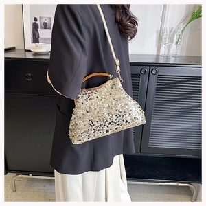 Borsa da sera con paillettes e manico ambrato indossata da una modella elegante