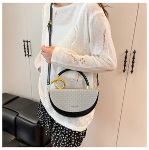 Detail of half-moon bag featuring woven texture and gold ring hardware on model