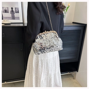 Detail of sequined evening clutch bag with gold chain strap on a model outfit