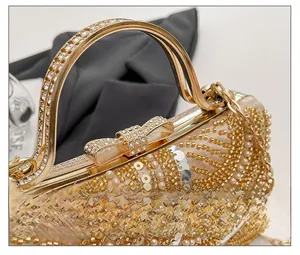 Close-up of champagne gold evening bag with bead embroidery and rhinestone bow clasp