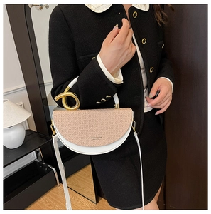 Detail of saddle bag featuring beige woven flap, gold ring handle, and white leather body