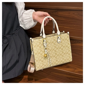 Detail of vintage monogram tote bag with white leather handles and bell charm pendant