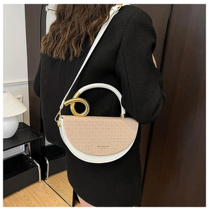 Detail of a two-tone saddle bag featuring woven texture and gold circular handle