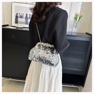 Detail of silver sequin evening shell bag with metal chain on a model outfit
