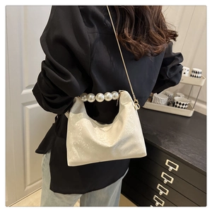 Detail of snake pattern leather bag with pearl handle and golden chain on model