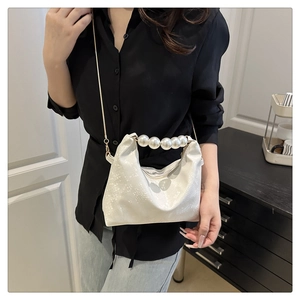 Detail view of large pearl handle and textured white material on stylish shoulder bag
