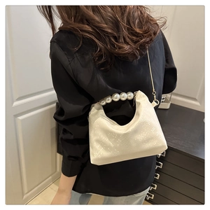 Close-up of elegant pearl handle and snake-textured white faux leather dumpling bag