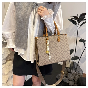 Macro detail of retro tote bag with monogram pattern and leather handle and tassel