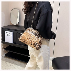 Detail of sequined evening clutch bag with gold chain strap worn by a model