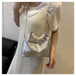 Close-up of silver snake-pattern bag featuring a large white pearl handle and metal chain