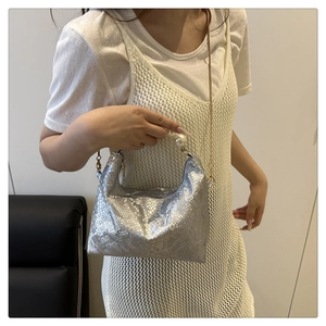 Close-up of silver snake-embossed underarm bag with pearl handle and gold chain detail