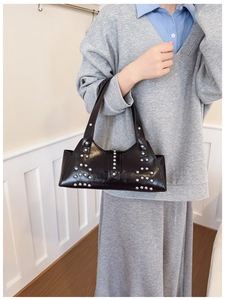 Detail of black oil-wax leather shoulder bag with silver rivet studs and dual handles