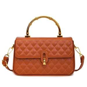 Caramel brown quilted handbag with gold bamboo handle and clasp on white background