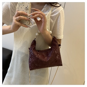 Detail of dark brown faux leather snakeskin bag with elegant pearl beaded handle