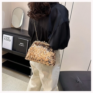 Detailed view of a gold sequin evening bag with metallic chain on a model shoulder