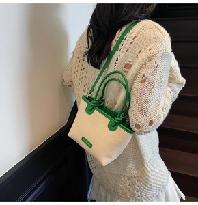 Dettaglio della borsa a secchiello in tela con finiture in pelle verde e logo moda
