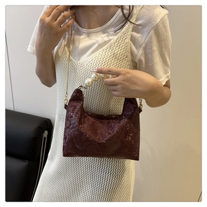Detail of dark wine red dumpling bag with snake skin texture and large pearl handle