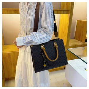 Detail shot of a large monogram tote bag with brown leather handles and nylon strap