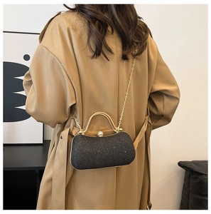 Détail de la pochette élégante à paillettes noires avec poignée dorée et bandoulière chaîne